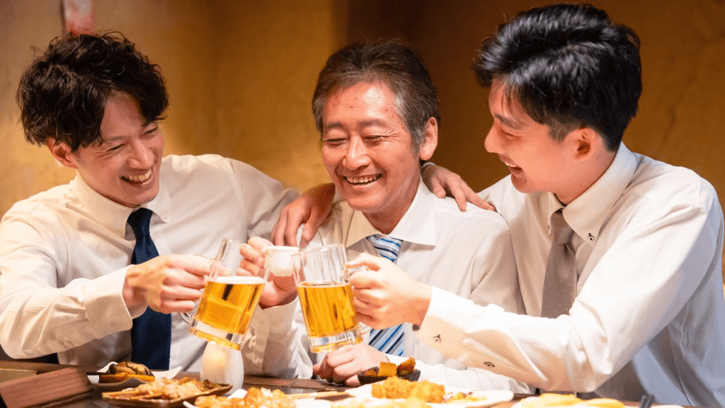 Empleados jóvenes y su superior brindando en un nomikai, después de una reunión de negocios.